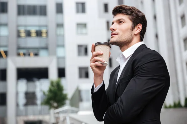 Thoughtful young businessman drinking take away coffee and thinking