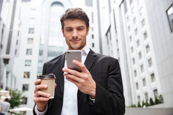 Geschäftsmann benutzt Handy und trinkt Kaffee in der Stadt — Stockfoto