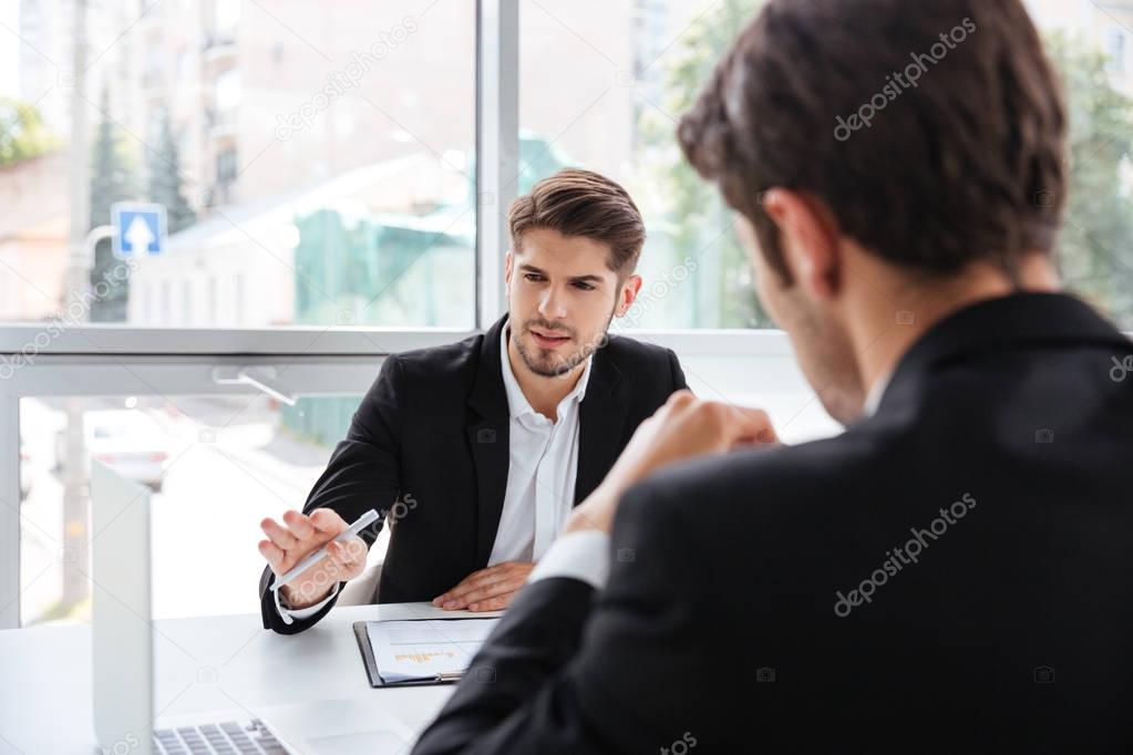Two businessmen working with laptop in office