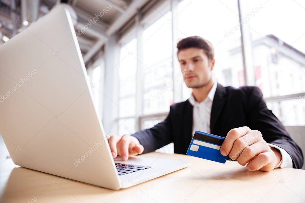 Businessman using laptop and credit card in office