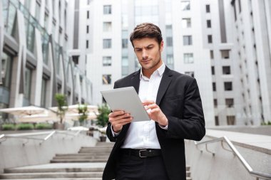 Yürüyüş ve şehirde tablet kullanarak ciddi iş adamı