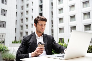 Laptop ile çalışma ve açık havada kahve içme işadamı