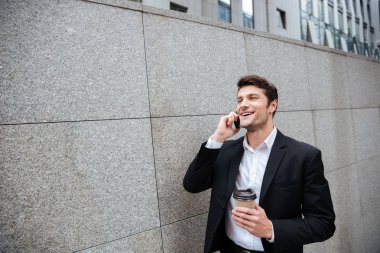 Cep telefonu üzerinde konuşurken ve açık havada kahve içme işadamı