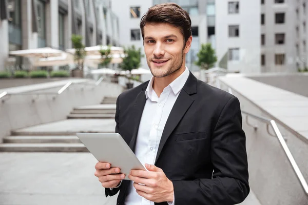 Attraktiver junger Geschäftsmann nutzt Tablet in der Nähe des Business Centers — Stockfoto