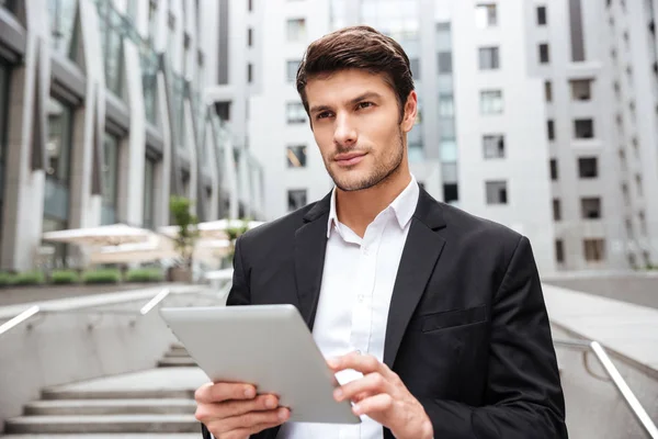 Hombre de negocios pensativo usando tableta en la ciudad —  Fotos de Stock
