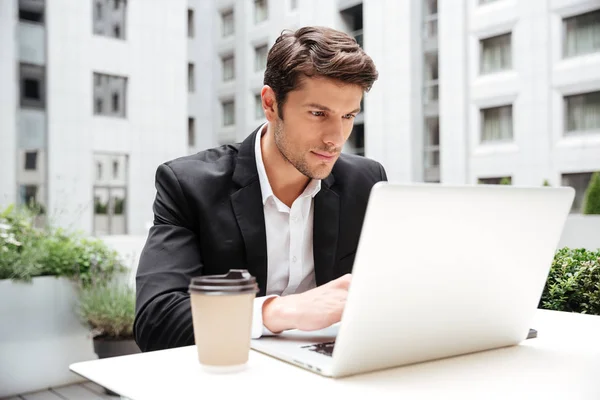 Biznesmen korzysta z laptopa w kawiarni na świeżym powietrzu — Zdjęcie stockowe