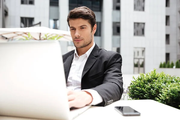 Businessman sitting and using laptop in outdoor cafe — Stock Photo, Image