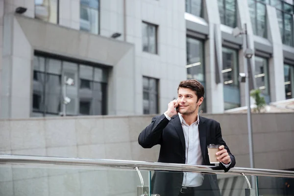 Feliz joven hombre de negocios hablando por teléfono celular y tomando café —  Fotos de Stock