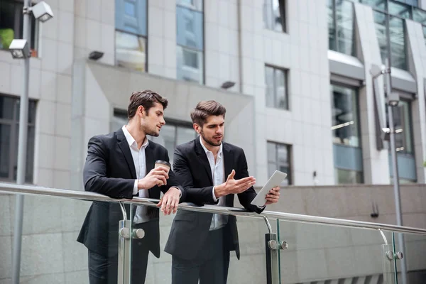 Twee zakenlieden praten en het gebruik van tablet in de stad — Stockfoto