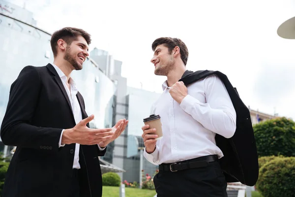 Deux jeunes hommes d'affaires joyeux buvant du café en plein air — Photo