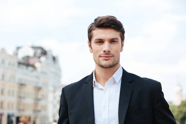 Handsome young businessman in suit standing outdoors — Stock Photo, Image