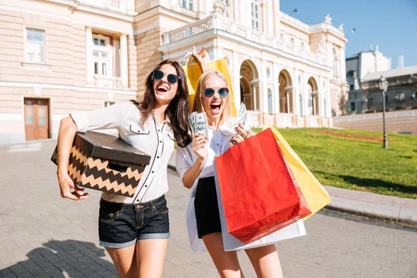 Dos mujeres jóvenes atractivas sosteniendo bolsas de compras y sonriendo —  Fotos de Stock