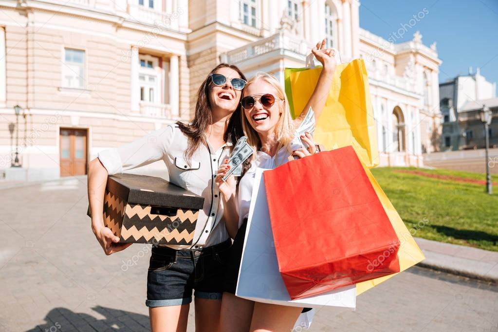 Two attractive girls standing with shopping bags on the street
