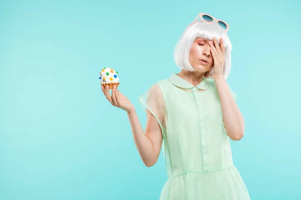 Unhappy depressed young woman stansing and holding cupcake — Stock Photo, Image