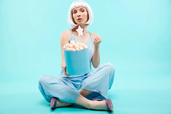 Vacker ung kvinna med marshmallows sitter och använder trollspö — Stockfoto