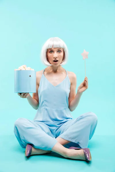 Förvånad blond ung kvinna håller marshmallows och magic stick — Stockfoto