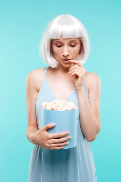 Attractive blonde young woman standing and looking at sweet marshmallows — Stock Photo, Image