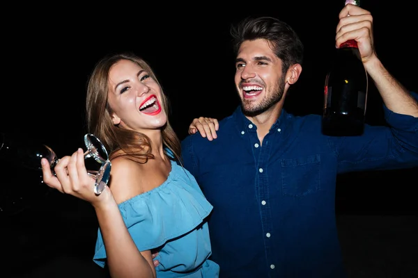 Happy young couple drinking champagne and laughing at night — Stock Photo, Image