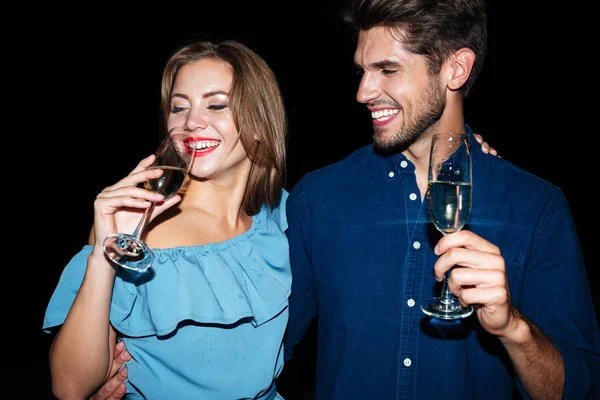Улыбающаяся молодая пара пьет шампанское по ночам вместе — стоковое фото