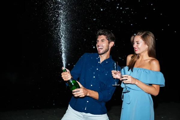 Couple opening bottle of champagne and having fun at night — Stock Photo, Image