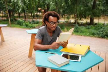 Afrika genç adam oturmuş ve kitap açık havada okuma konsantre