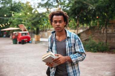 Adam sırt çantası ve parkta duran kitaplar