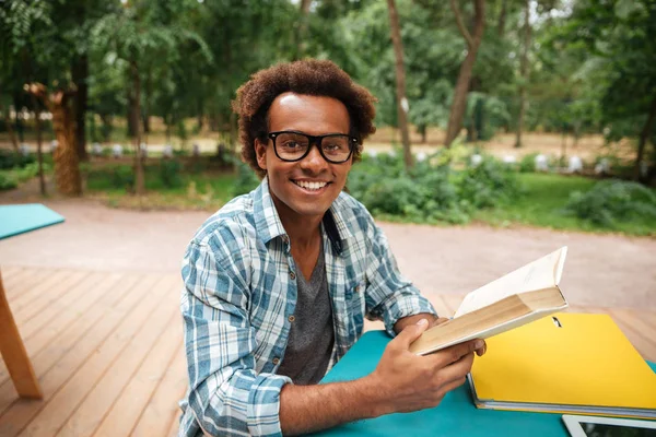 Jovem africano alegre lendo livro ao ar livre — Fotografia de Stock