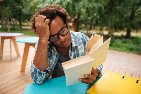 Doordachte Afrikaanse jongeman lezen boek buitenshuis — Stockfoto