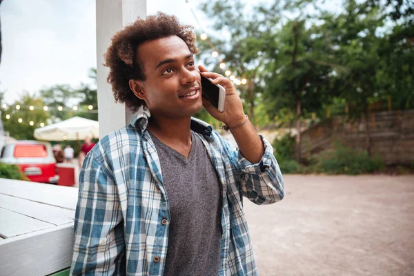 Gelukkig Afrikaanse jonge man praten op mobiele telefoon buitenshuis — Stockfoto
