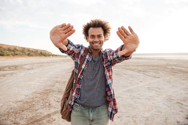 Glada afrikanska man fokuserat genom händerna på stranden — Stockfoto