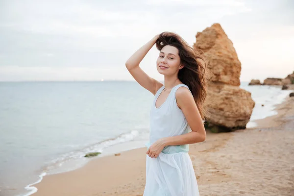 Mulher feliz em vestido branco em pé na praia — Fotografia de Stock