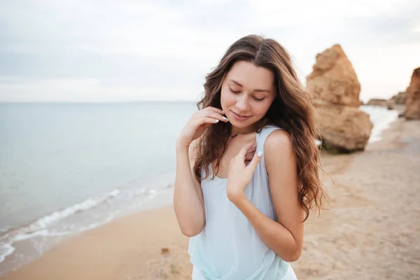 Linda mujer joven con el pelo largo de pie en la playa — Foto de Stock