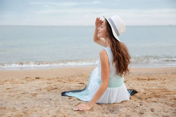 Happy woman sitting on the beach and looking far away — Stock Photo, Image