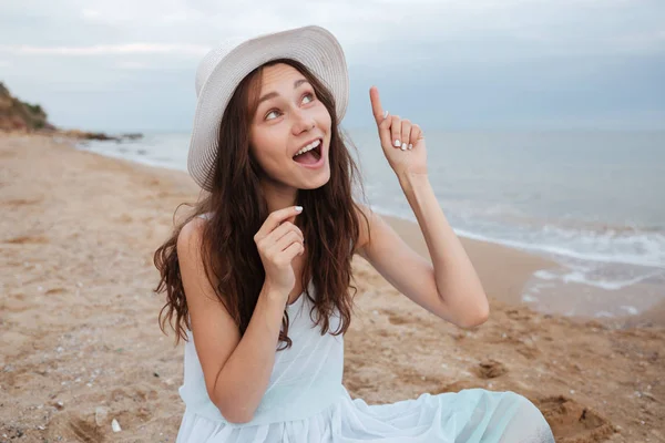Mujer feliz señalando hacia arriba y teniendo idea en la playa — Foto de Stock