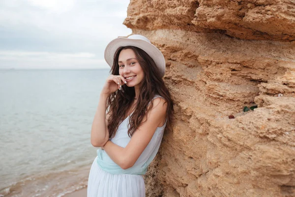 Menina bonito alegre de pé perto da rocha na praia — Fotografia de Stock