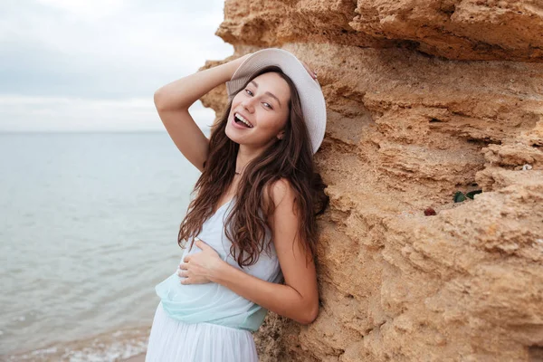 Mujer feliz de pie cerca de la roca en la playa — Foto de Stock