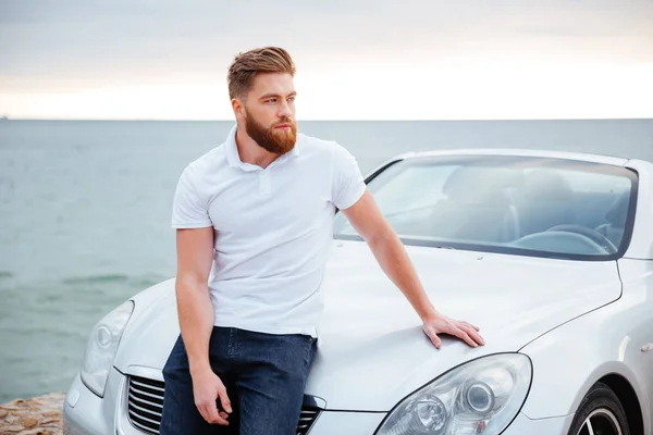 Молодий бородатий чоловік спирається на свою машину — стокове фото