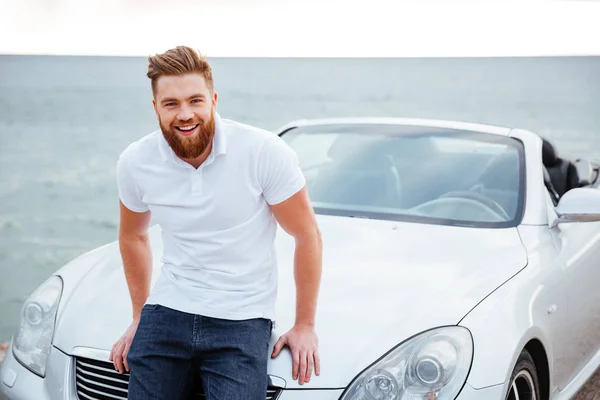 Alegre hombre barbudo sonriente de pie en su nuevo coche —  Fotos de Stock