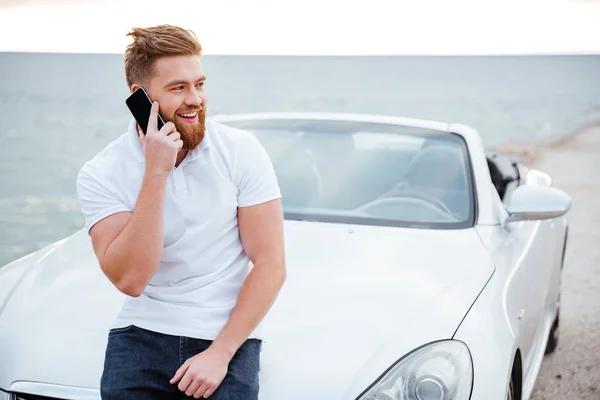 Mann telefoniert mit Handy, während er sich an Auto lehnt — Stockfoto
