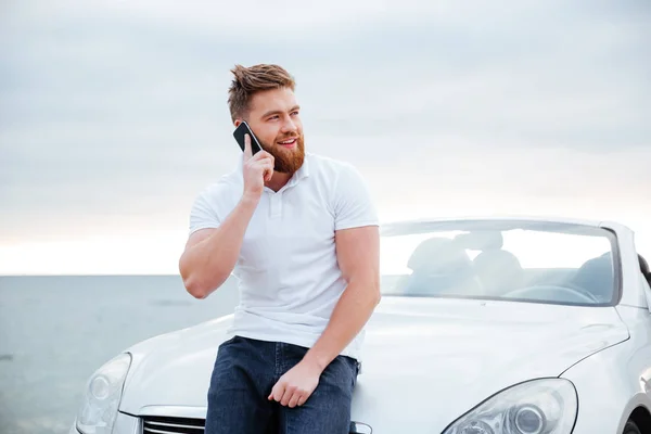 Man, praten over de mobiele telefoon terwijl leunend op auto — Stockfoto