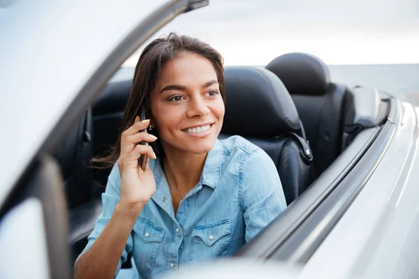 Красивая женщина водит машину и разговаривает по мобильному телефону — стоковое фото