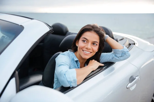 Glada leende brunett kvinna vilar inuti hennes cabriolet — Stockfoto