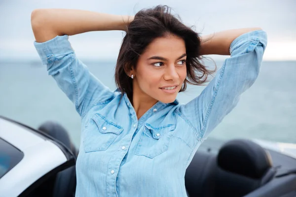 Frau steht neben ihrem neuen Auto am Meer — Stockfoto