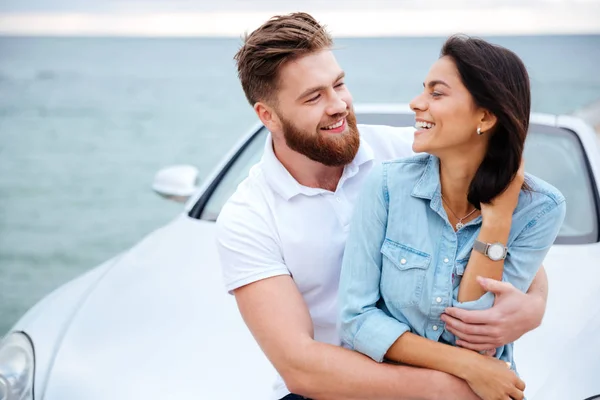 Ungt par embracing stående nära bil vid havet — Stockfoto