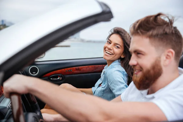 Alegre pareja sonriendo mientras monta en su coche descapotable —  Fotos de Stock