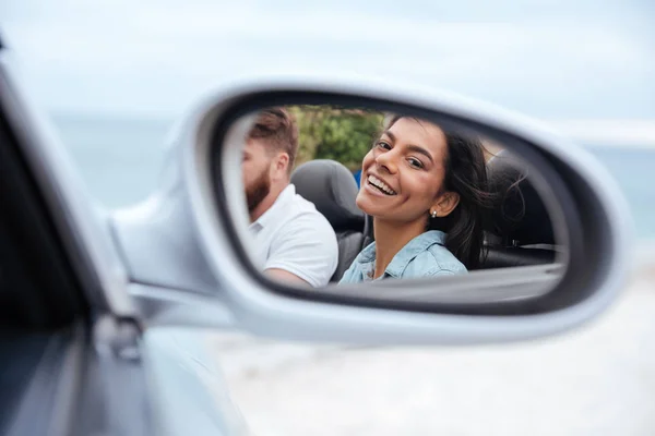 Schöne Frau, die ihr Spiegelbild im Spiegel ihres Autos betrachtet — Stockfoto