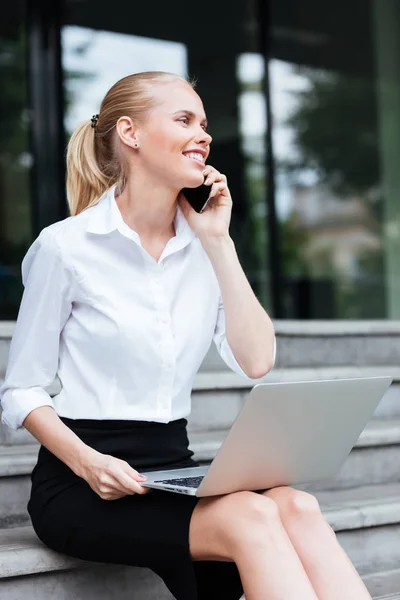 Kobieta interesu laptop i telefon, siedząc na schodach — Zdjęcie stockowe