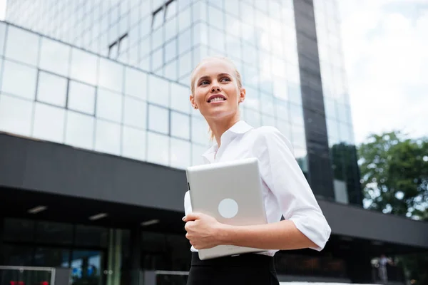 Donna d'affari in possesso di tablet digitale, mentre guardando lontano contro edificio per uffici — Foto Stock
