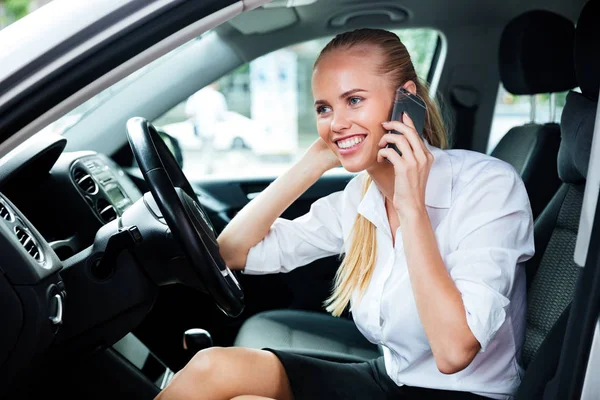 Улыбающаяся деловая женщина за рулем машины и разговаривающая по мобильному телефону — стоковое фото