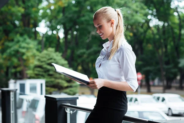Happy young business woman standing and holding folders — Stock Photo, Image
